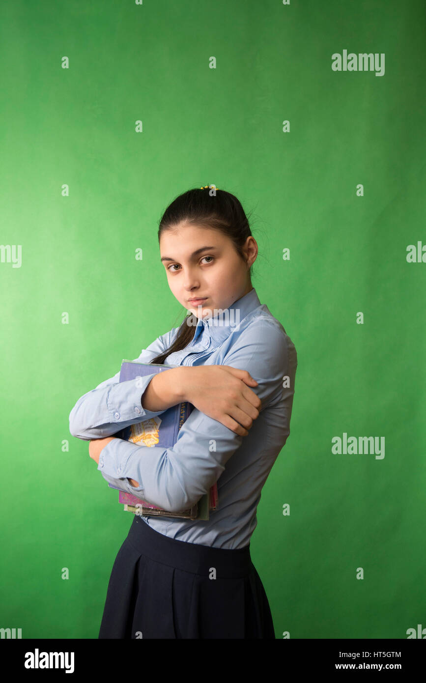 Teen ragazza con i capelli lunghi in maglietta blu in possesso di una pila di libri nelle sue mani Foto Stock