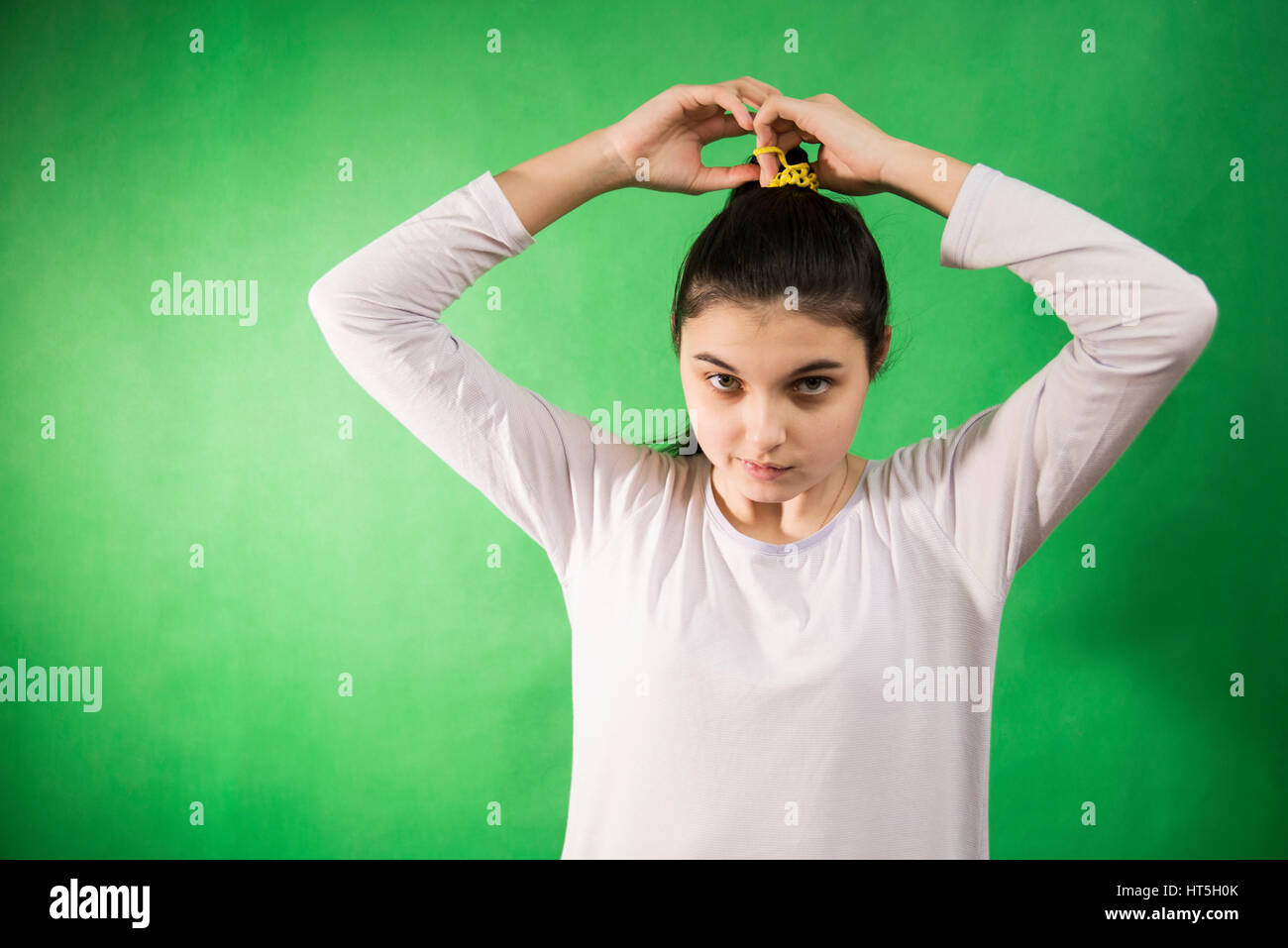 Teen girl in nightie pettinare i capelli a verde chroma key sullo sfondo Foto Stock