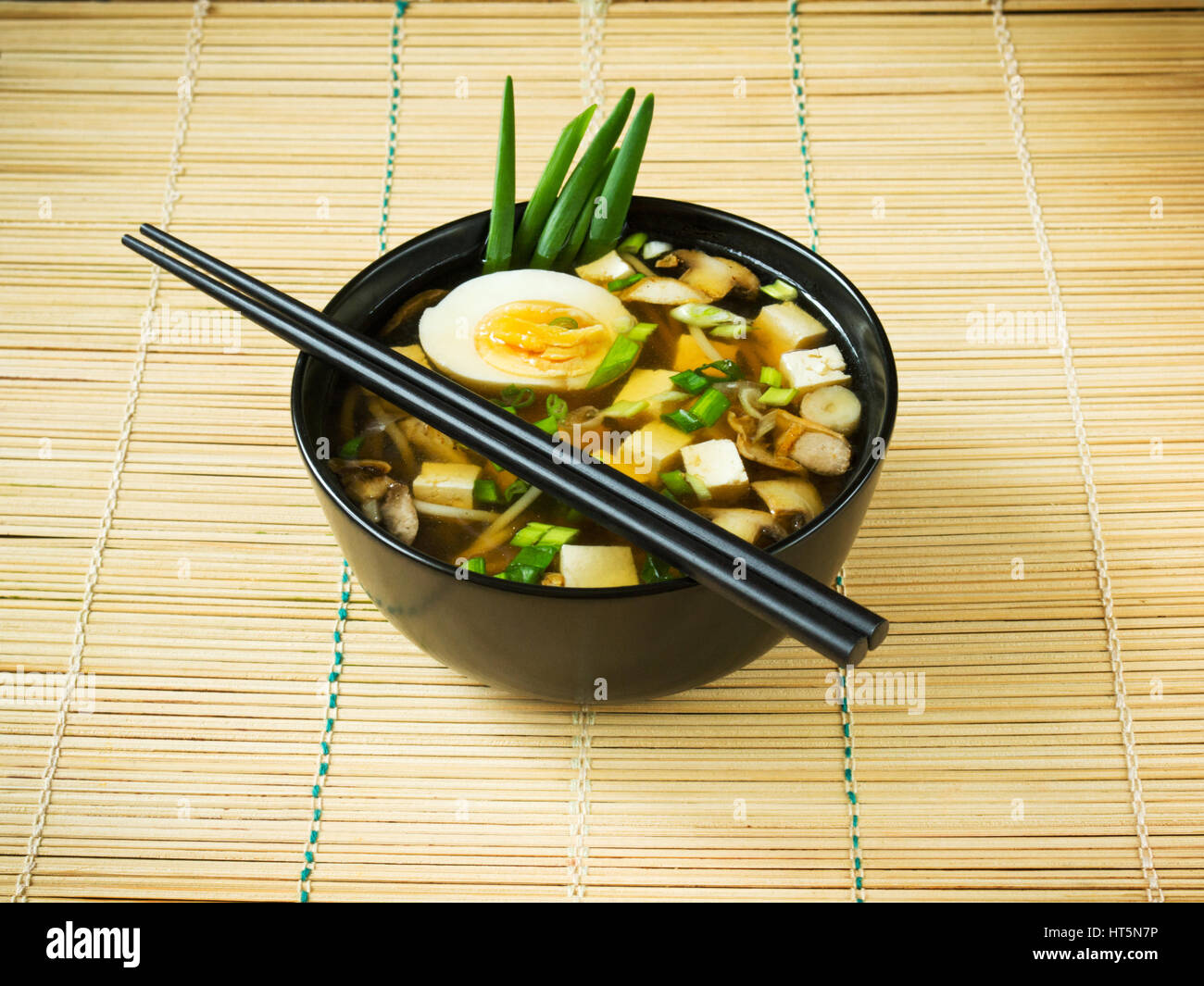 Giapponese zuppa di miso in nero ciotola sul tappetino di bambù Foto stock  - Alamy
