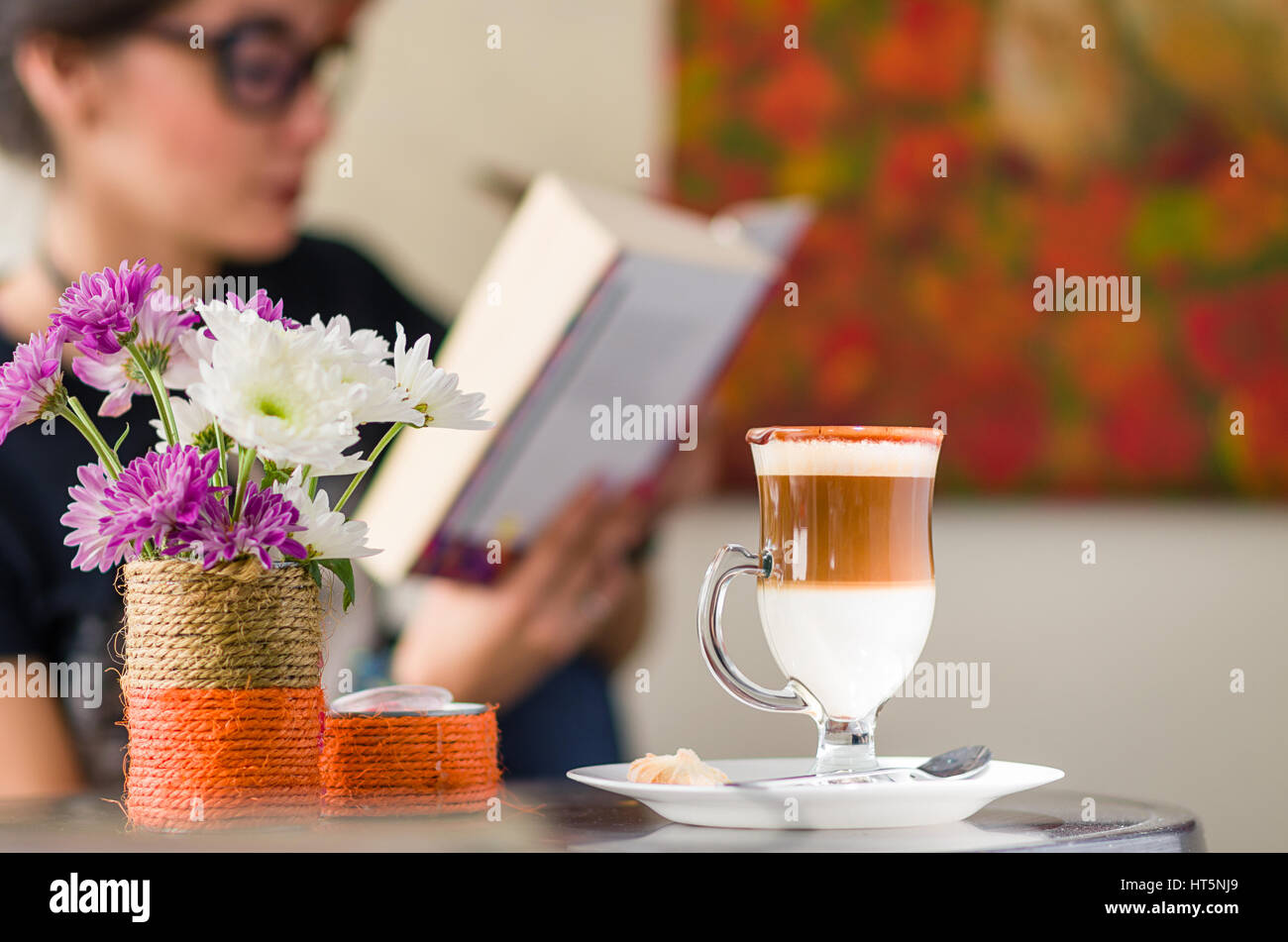 Ragazza di bere il cappuccino all'interno di un Art cafe durante la lettura di un libro Foto Stock