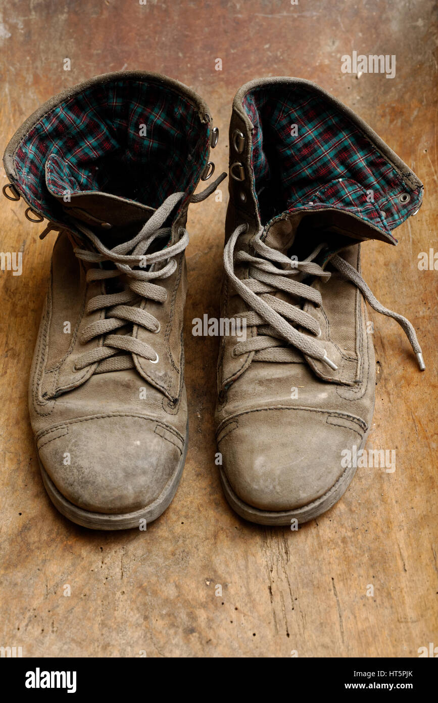 Coppia di vecchie scarpe di cuoio, logore e polverosa, su sfondo di legno Foto Stock