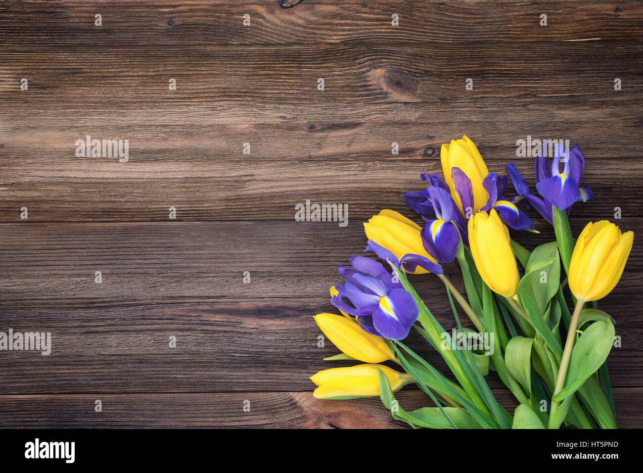 Bouquet di fiori. Tulipani gialli e iride fiori su legno rustico sfondo. Table top visualizzare e copiare lo spazio per testo Foto Stock