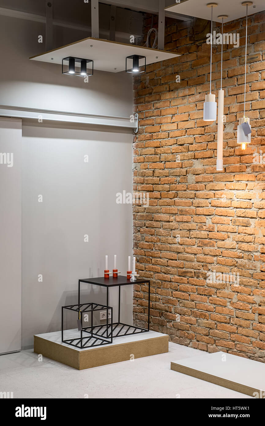 Interno in stile loft con il grigio e le pareti in mattoni. Ci sono appese le lampade incandescenti, nero di piccole tavole di metallo con candelieri. Verticale. Foto Stock