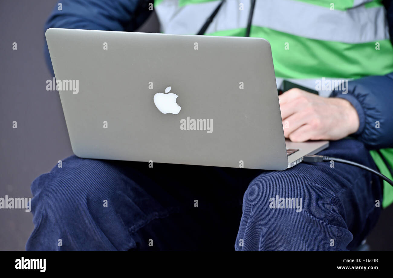 Fotografo utilizzando un MacBook Pro Apple computer portatile per inviare le immagini dal lato del campo di calcio Foto Stock