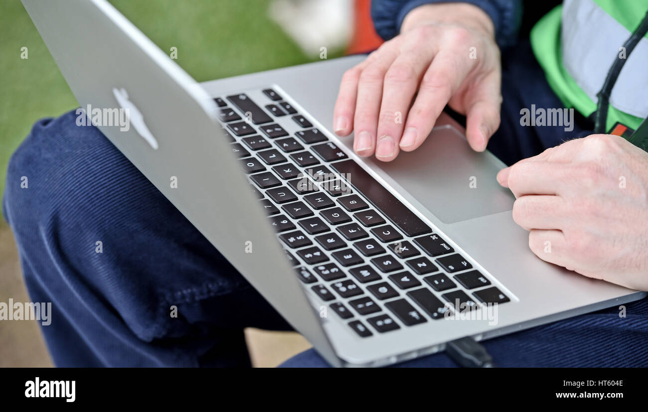 Fotografo utilizzando un MacBook Pro Apple computer portatile per inviare le immagini dal lato del campo di calcio Foto Stock