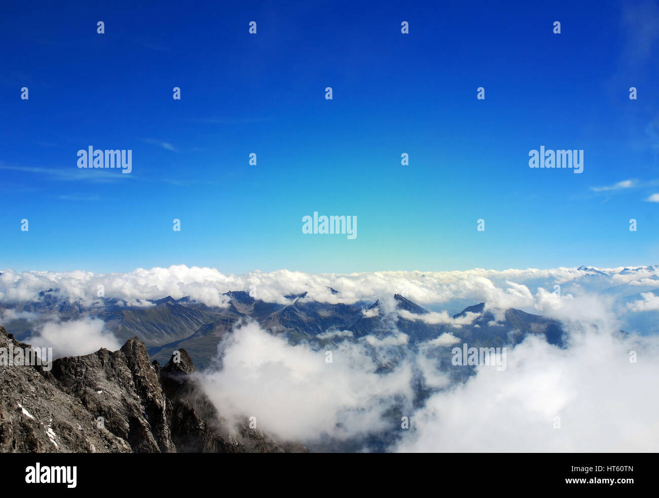 Magnifica vista sulle Alpi al di sopra dei picchi di montagna in Francia, con galleggiante soffici nuvole bianche di seguito e orizzonte contro il cielo blu Foto Stock