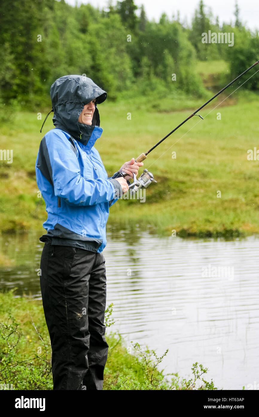 Donna con la canna da pesca in condizioni di tempo piovoso Foto Stock