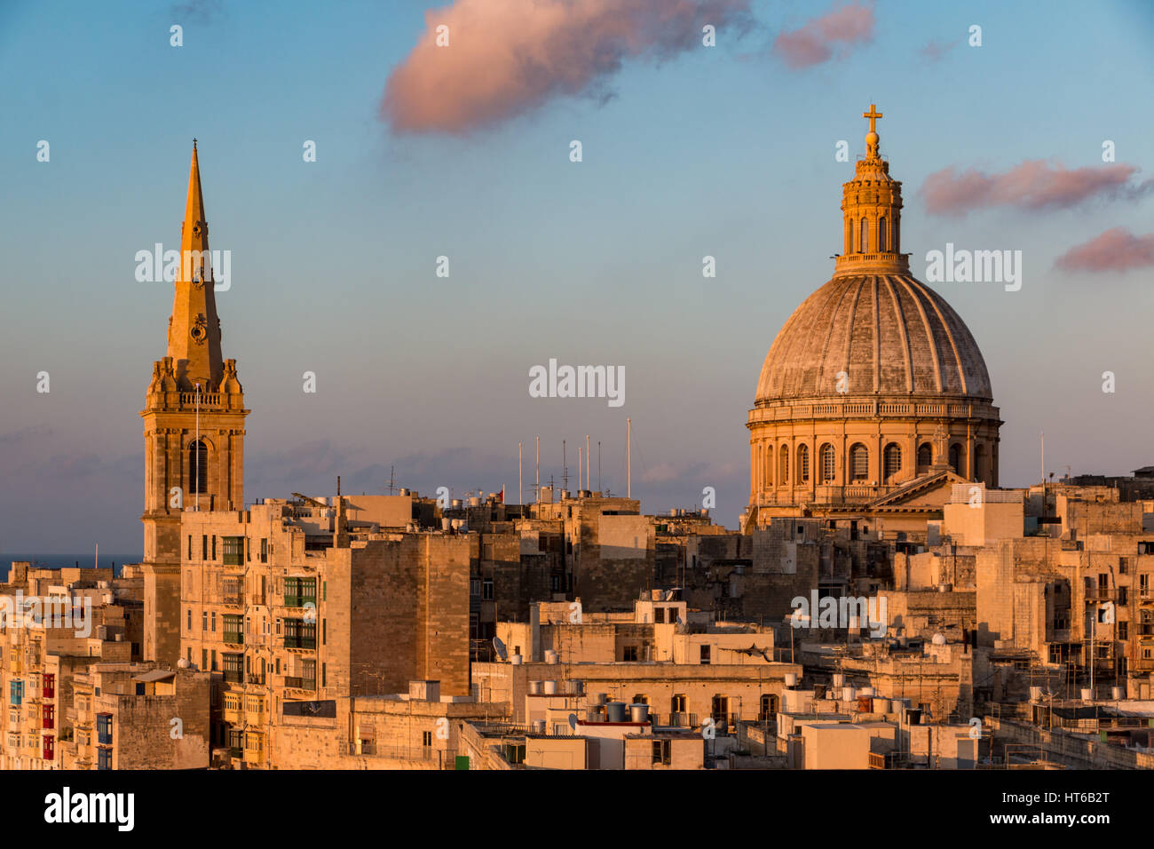 Una guglia della chiesa e la cupola a La Valletta, Malta al tramonto Foto Stock