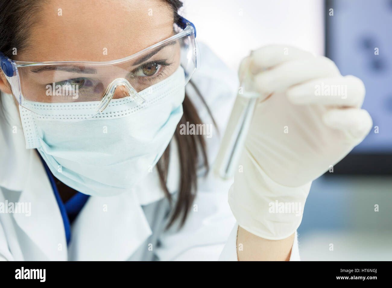 Femmina o medico scienziato o medico utilizzando guardando un tubo di prova di una soluzione chiara in un laboratorio o in laboratorio Foto Stock