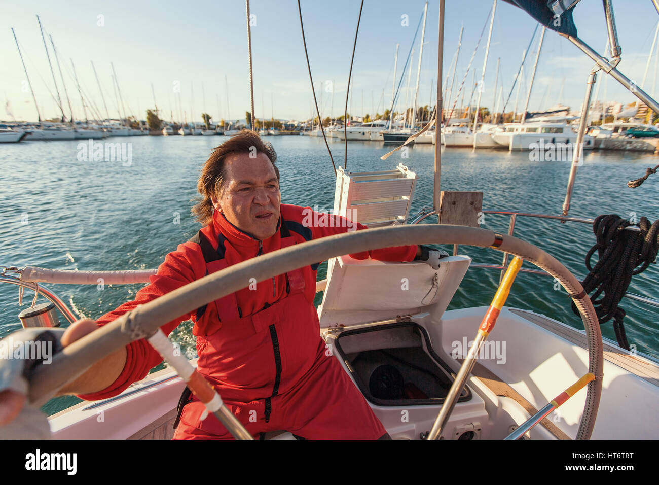 L'uomo skipper al timone controlla di uno yacht a vela. Foto Stock