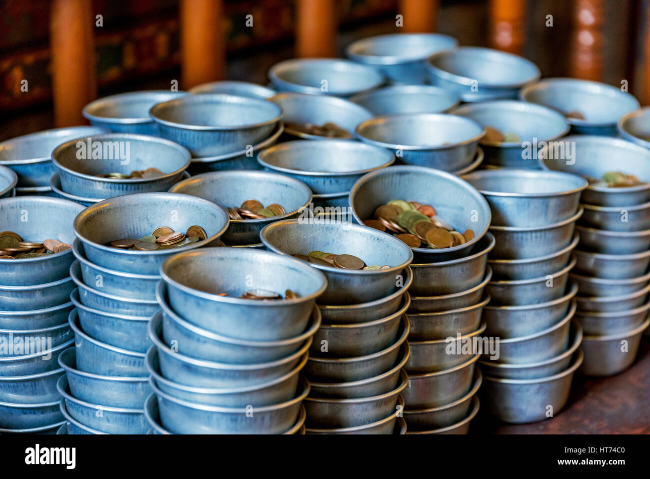 Monete in ciotole di donazione per un tempio buddista in Thailandia Foto Stock