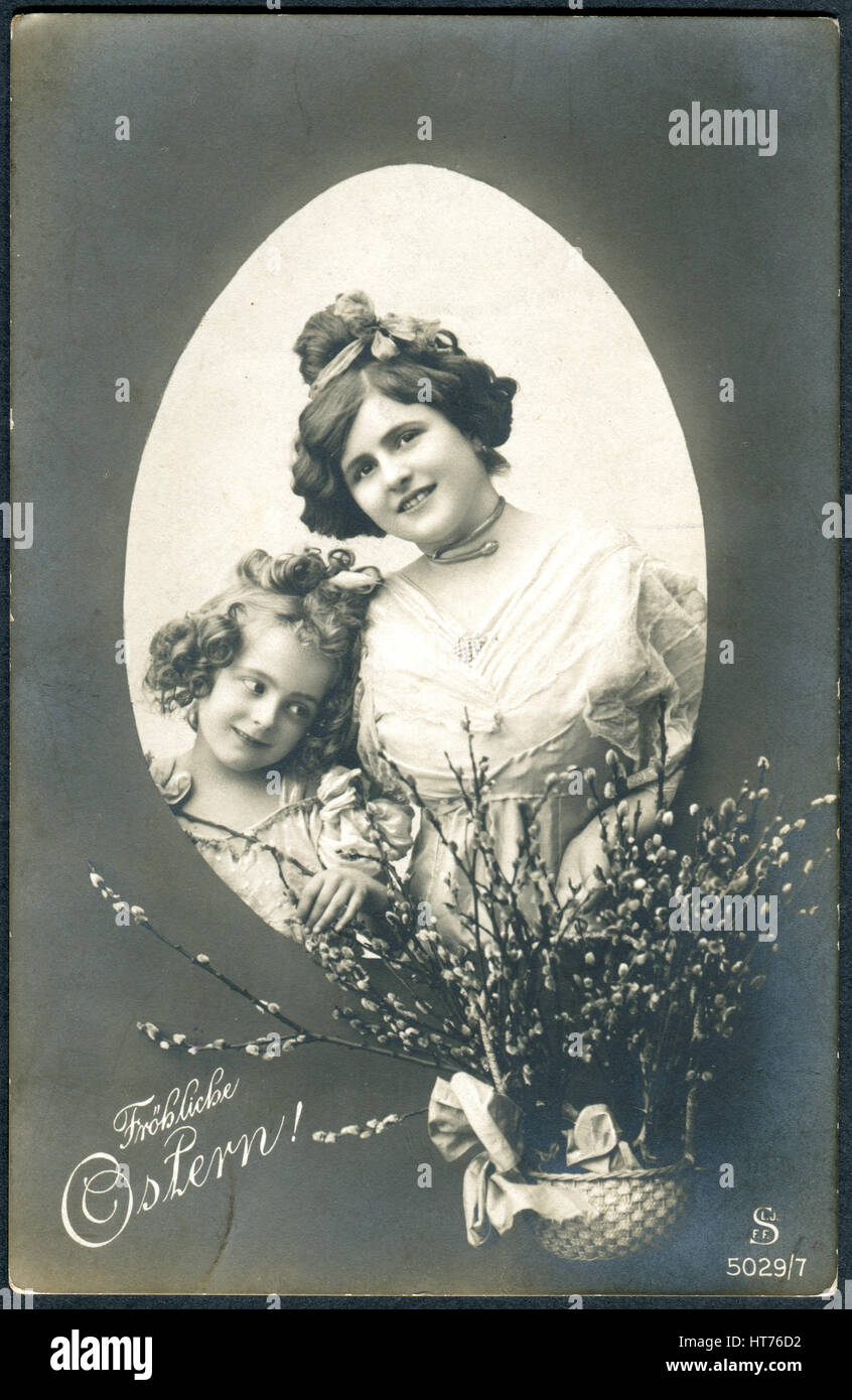 Una cartolina A Stampato in Germania, mostra una madre e figlia e un cestello con i rami di salici. Iscrizione in tedesco: Buona Pasqua Foto Stock