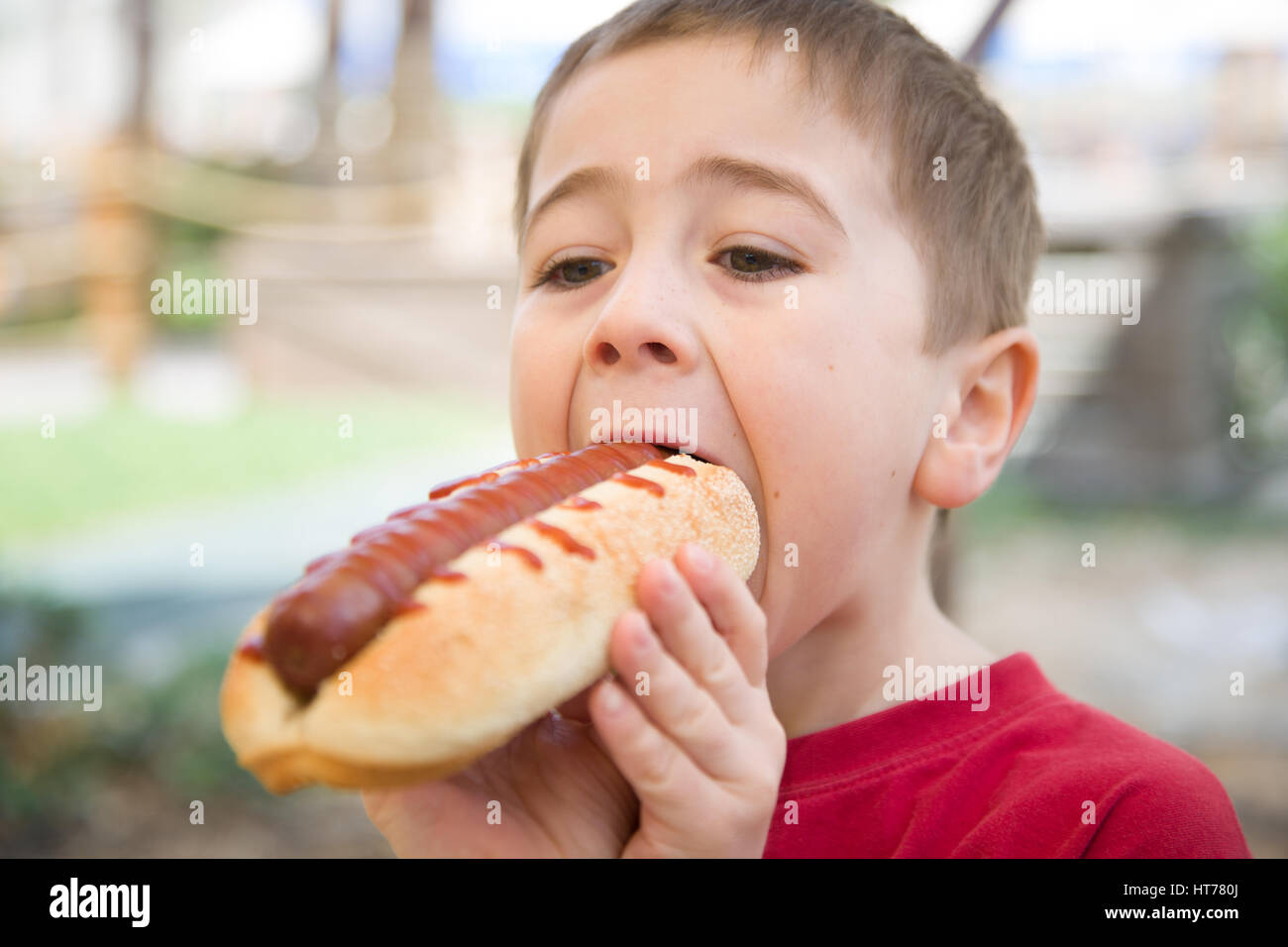 Little Boy mangia un enorme hot-dog panino Foto Stock