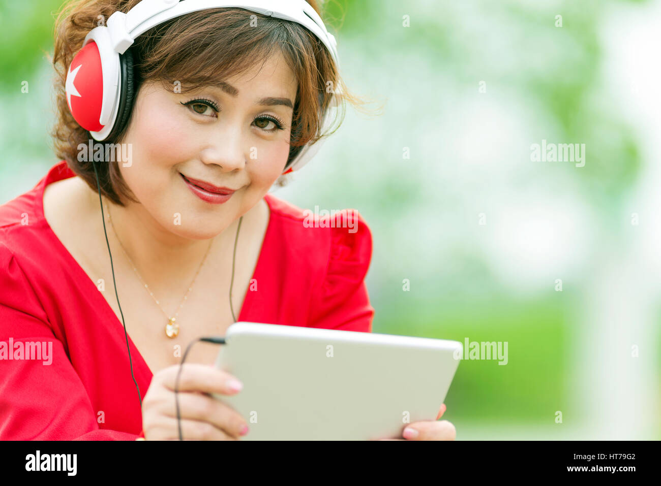Donna felice navigando tablet e ascoltare musica su cuffie a casa Foto Stock