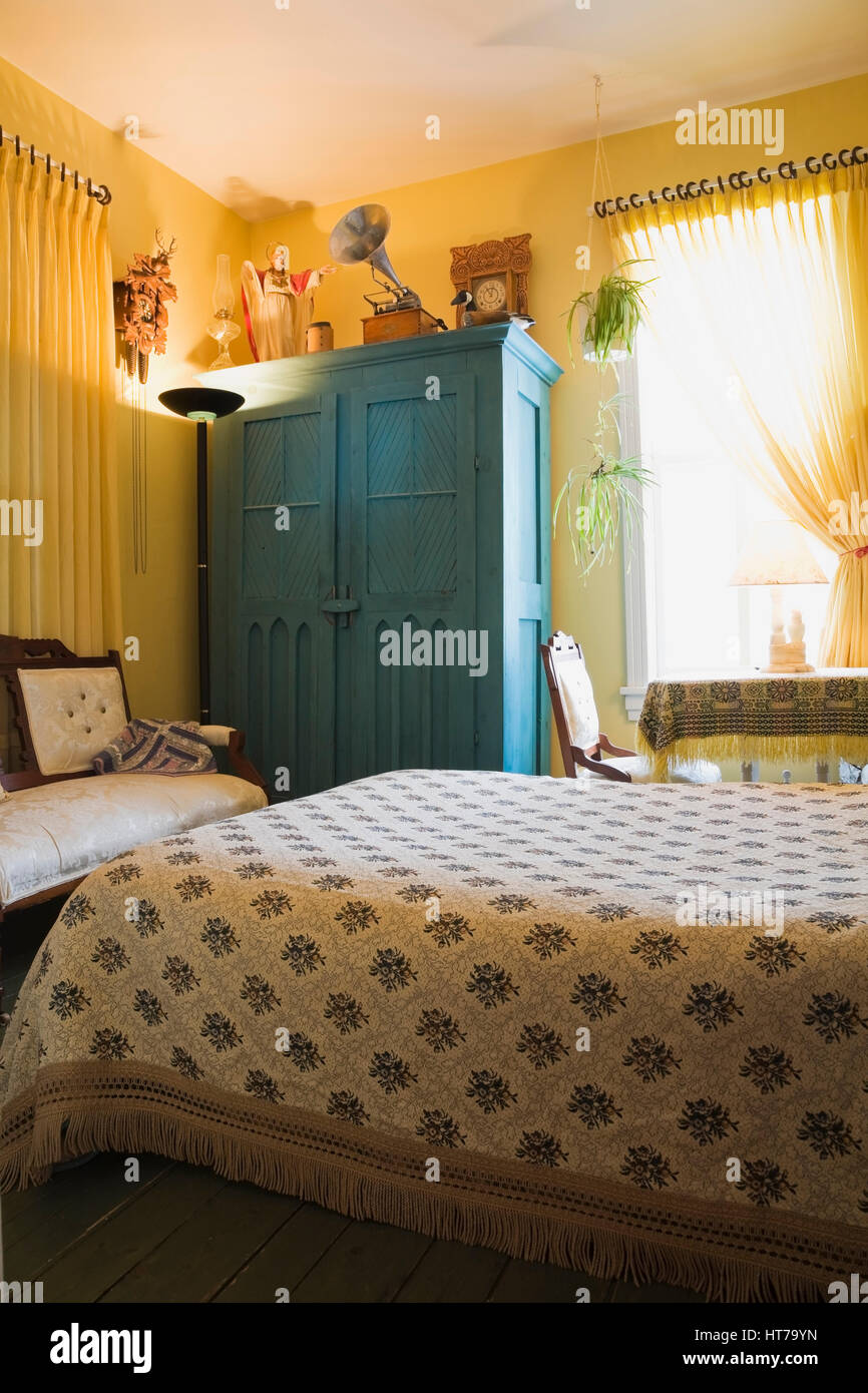 La camera da letto padronale con copriletto dai motivi floreali e un armadio in legno in stile vittoriano 1904 vecchia casa interni. Foto Stock
