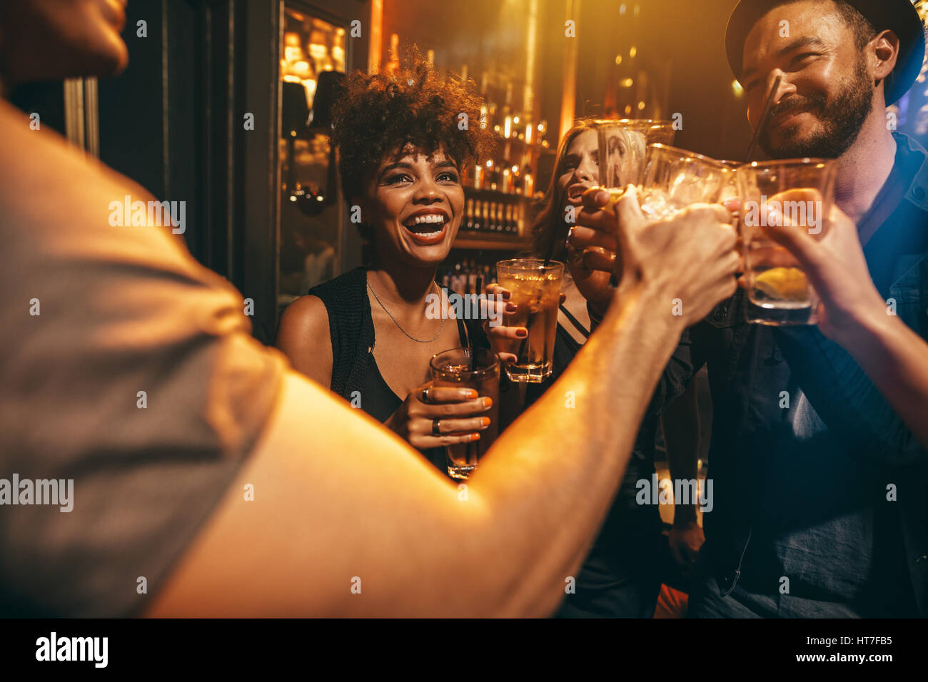 Un gruppo di giovani la tostatura bevande al night club. Giovani uomini e donne avendo divertimento presso il lounge bar. Foto Stock