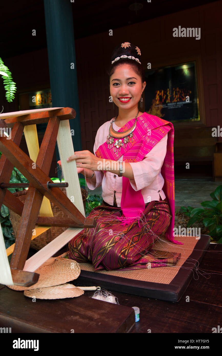 Giovane donna Thai in abito tradizionale seta di filatura a Jim Thompson House. Foto Stock