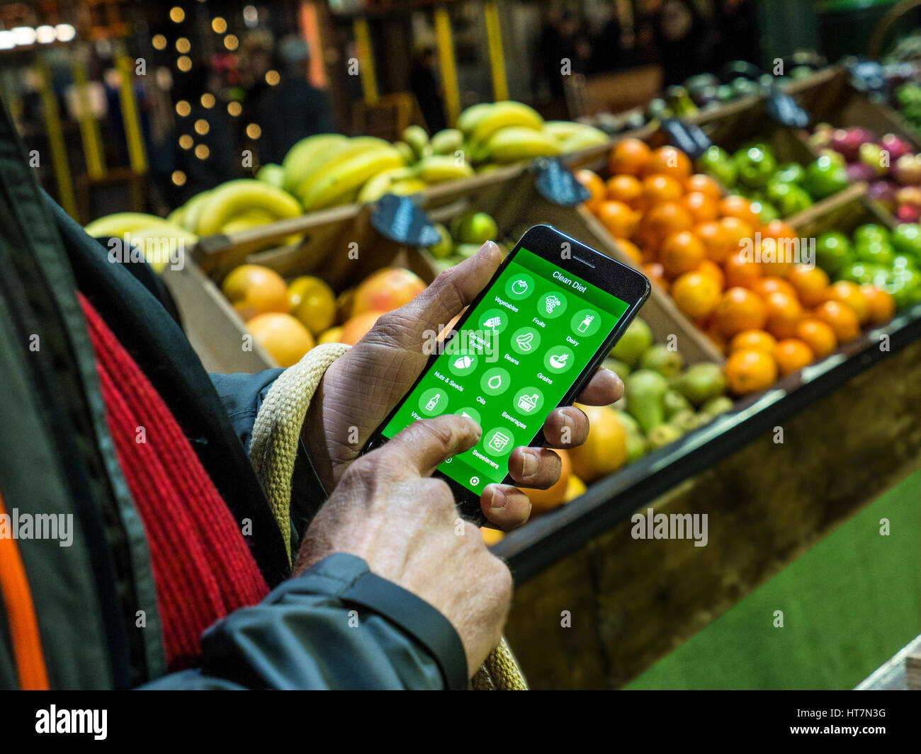 L'uomo tiene iPhone 7plus lo smartphone utilizzando detox app per suggerimenti per produrre disintossicante dieta nel mercato di Borough Southwark London REGNO UNITO Foto Stock