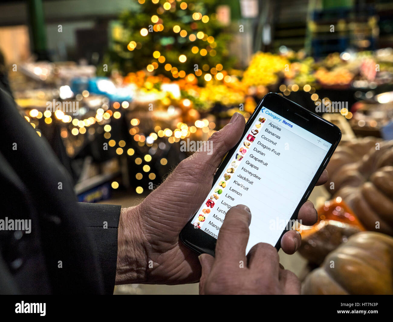 Mano azienda smartphone iPhone 7plus interattiva con frutta e verdura suggerimenti sullo schermo nel mercato di Borough London REGNO UNITO Foto Stock