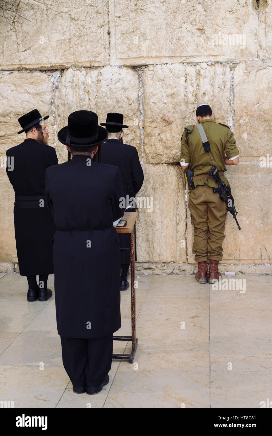 Un soldato e gli ebrei ortodossi pregano presso la Western il Muro del Pianto a Gerusalemme, Israele Foto Stock