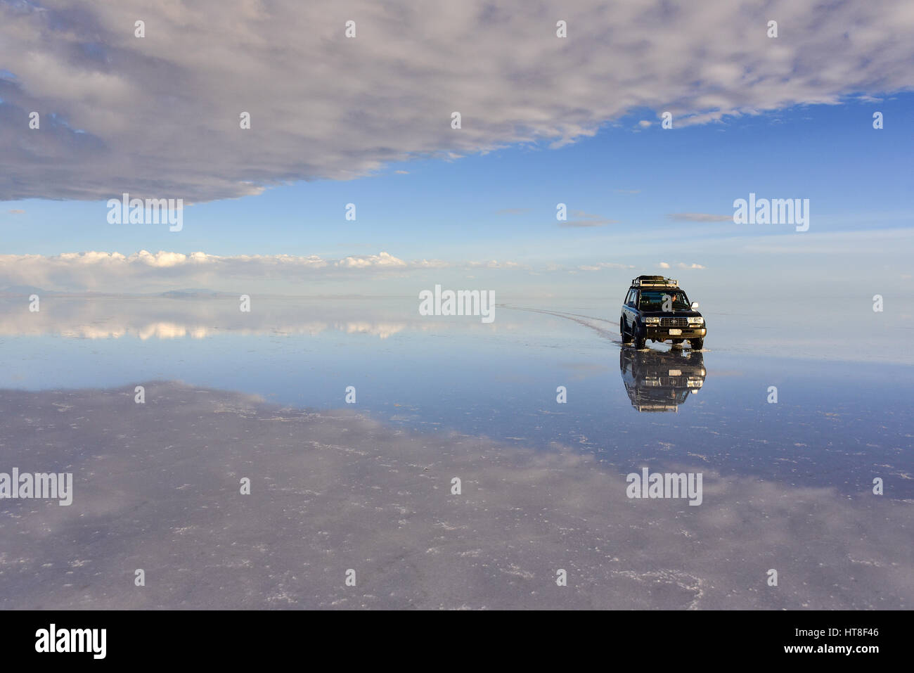 Tutti i terreni a veicolo in marcia su un lago, acqua allagata Salt Lake, Salar de Uyuni, altiplano, Bolivia Foto Stock
