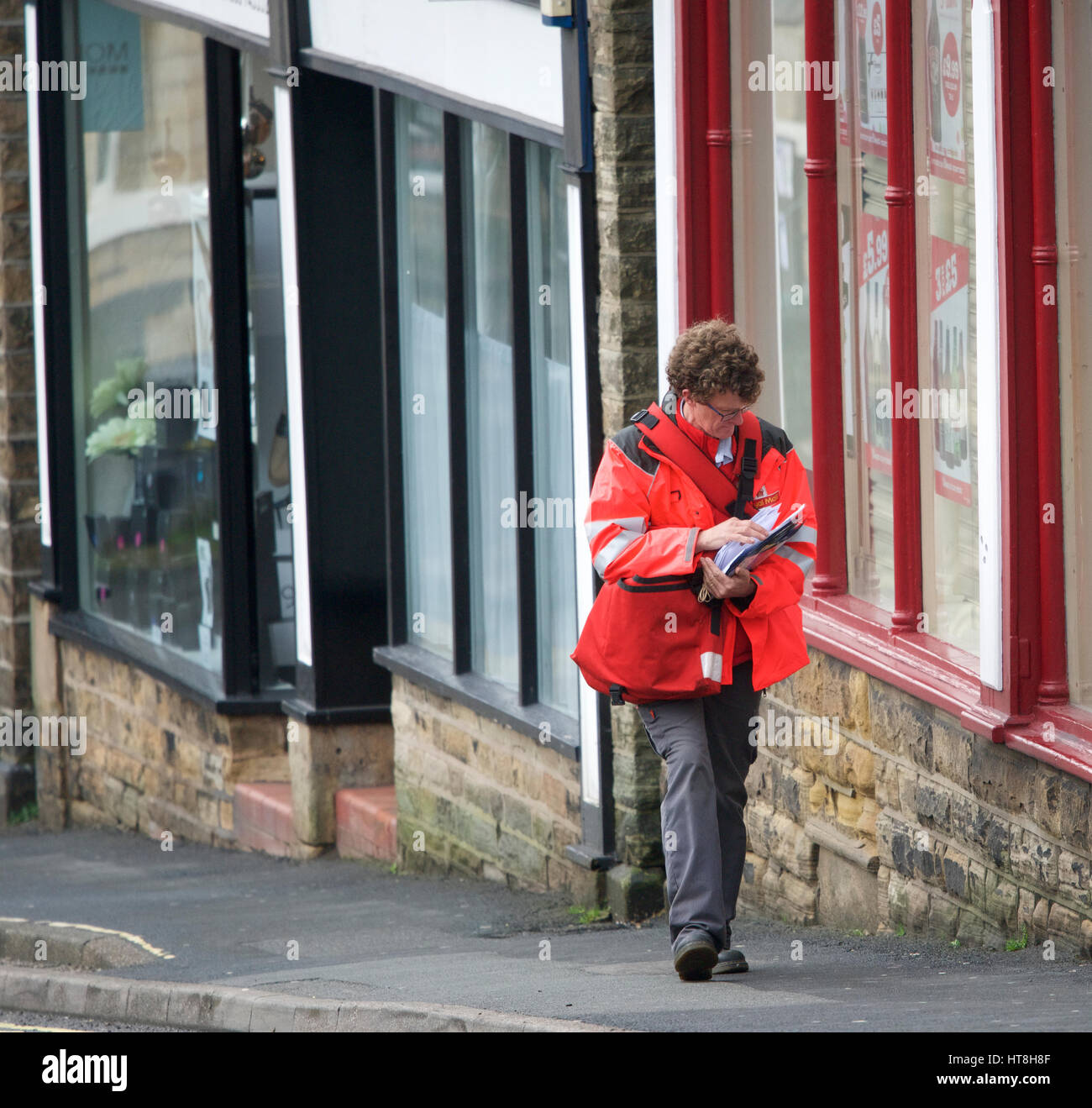 Un postino sul suo giro di recapito in New Mills, Derbyshire Foto Stock