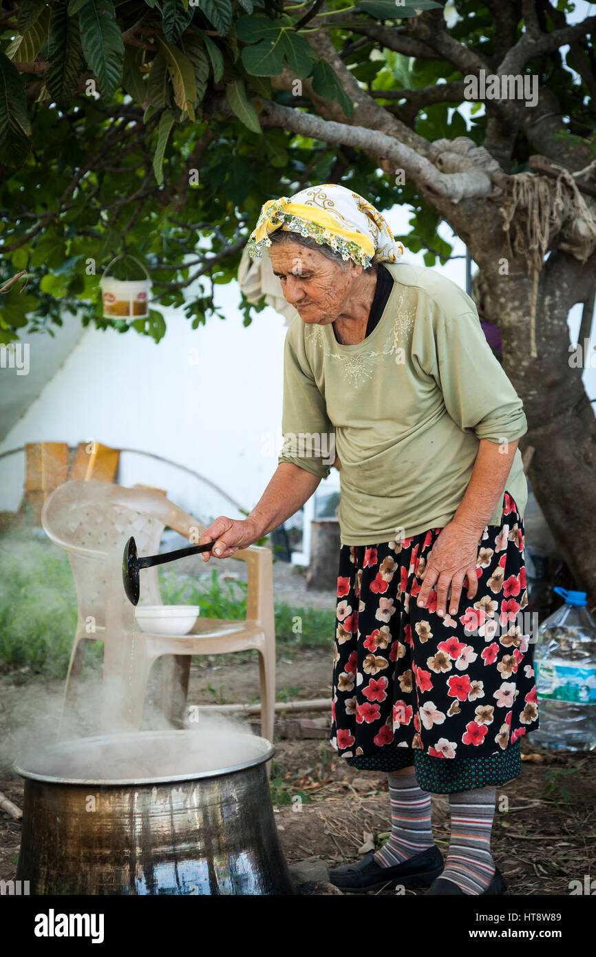 Vecchia donna cucinare all'aperto, Selimiye, Bozburun Penisola, Turchia Foto Stock