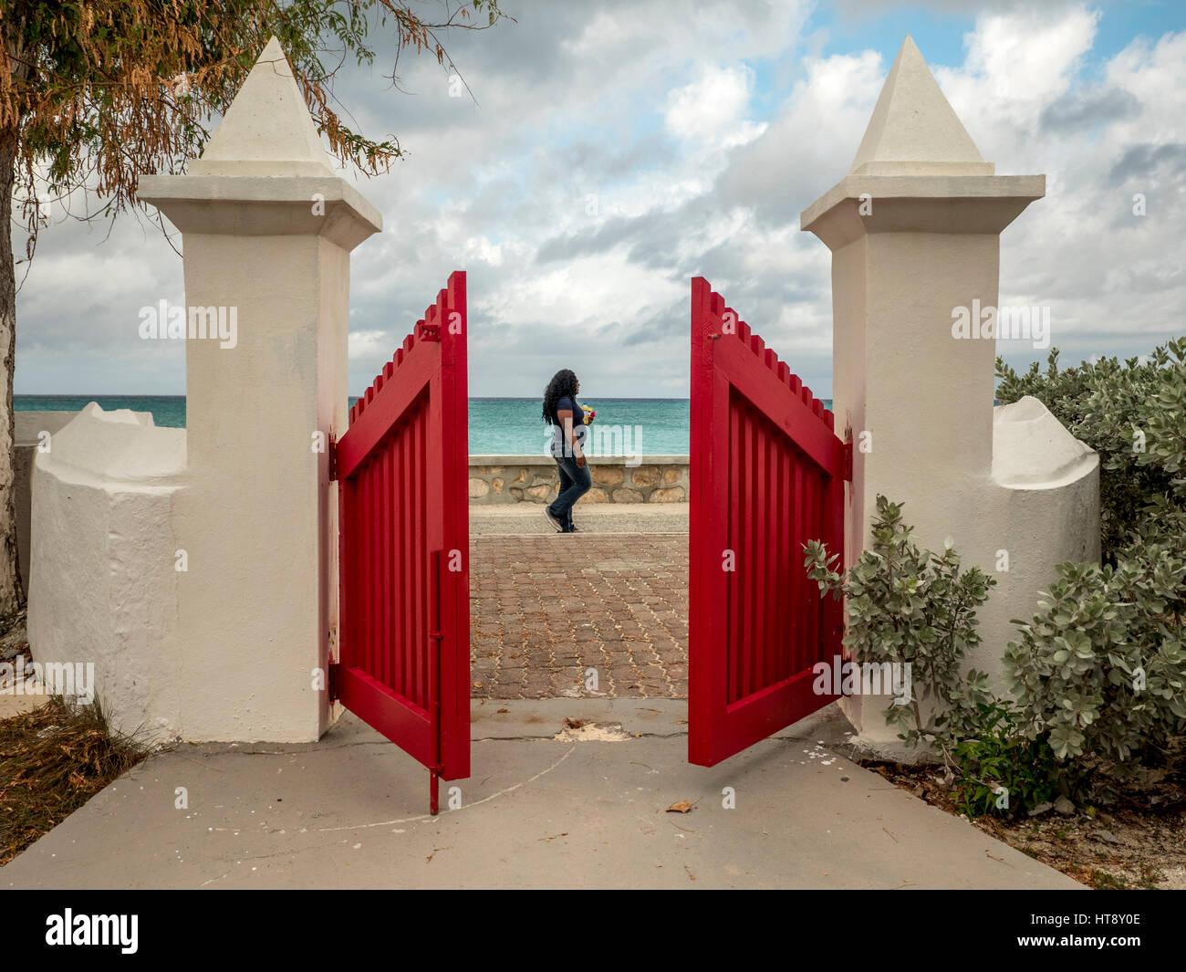 Donna locale passeggiate oltre i cancelli del St Mary's Anglican Pro Chiesa Cattedrale Cockburn Town Grand Turk, Isole Turks e Caicos Foto Stock