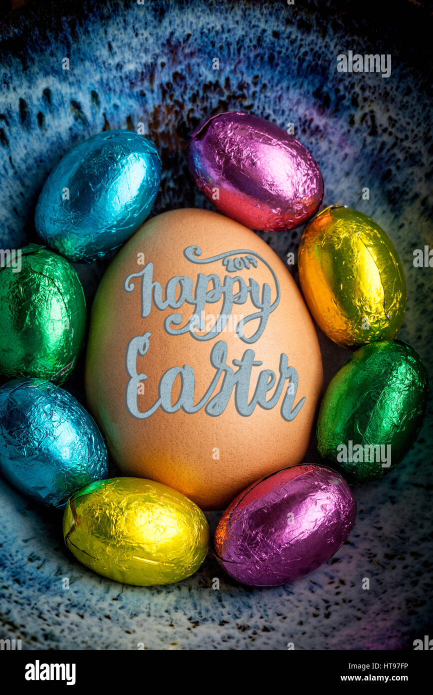 Felice Pasqua 2017 scritte sui uovo rivestita con piccole uova di cioccolato avvolto in foglio colorato. L'immagine verticale Foto Stock
