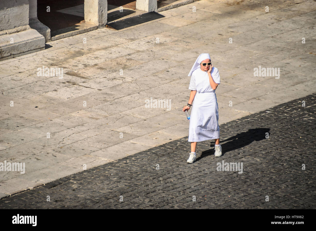 Loreto, Italia, 14 Lug 2013 - giovane debuttante Nun a piedi e chiacchierare al telefono nella piazza principale di Loreto, un famoso pellegrinaggio santuario in Italia Foto Stock