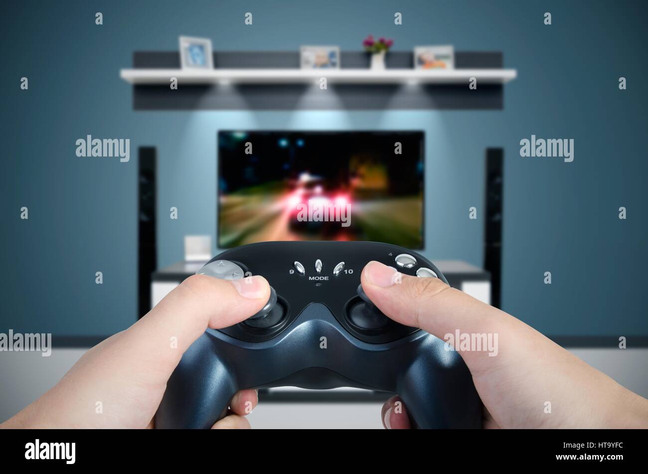 Tenere le mani il controller di gioco. L'uomo la riproduzione di una vettura da corsa su TV in camera moderna Foto Stock