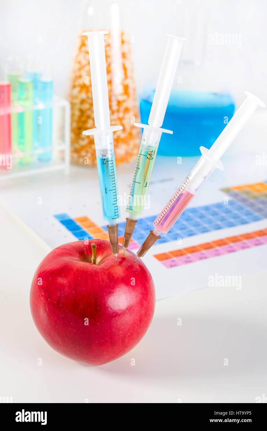Tre siringhe in rosso apple. Alimenti geneticamente modificati in lab concept. Foto Stock