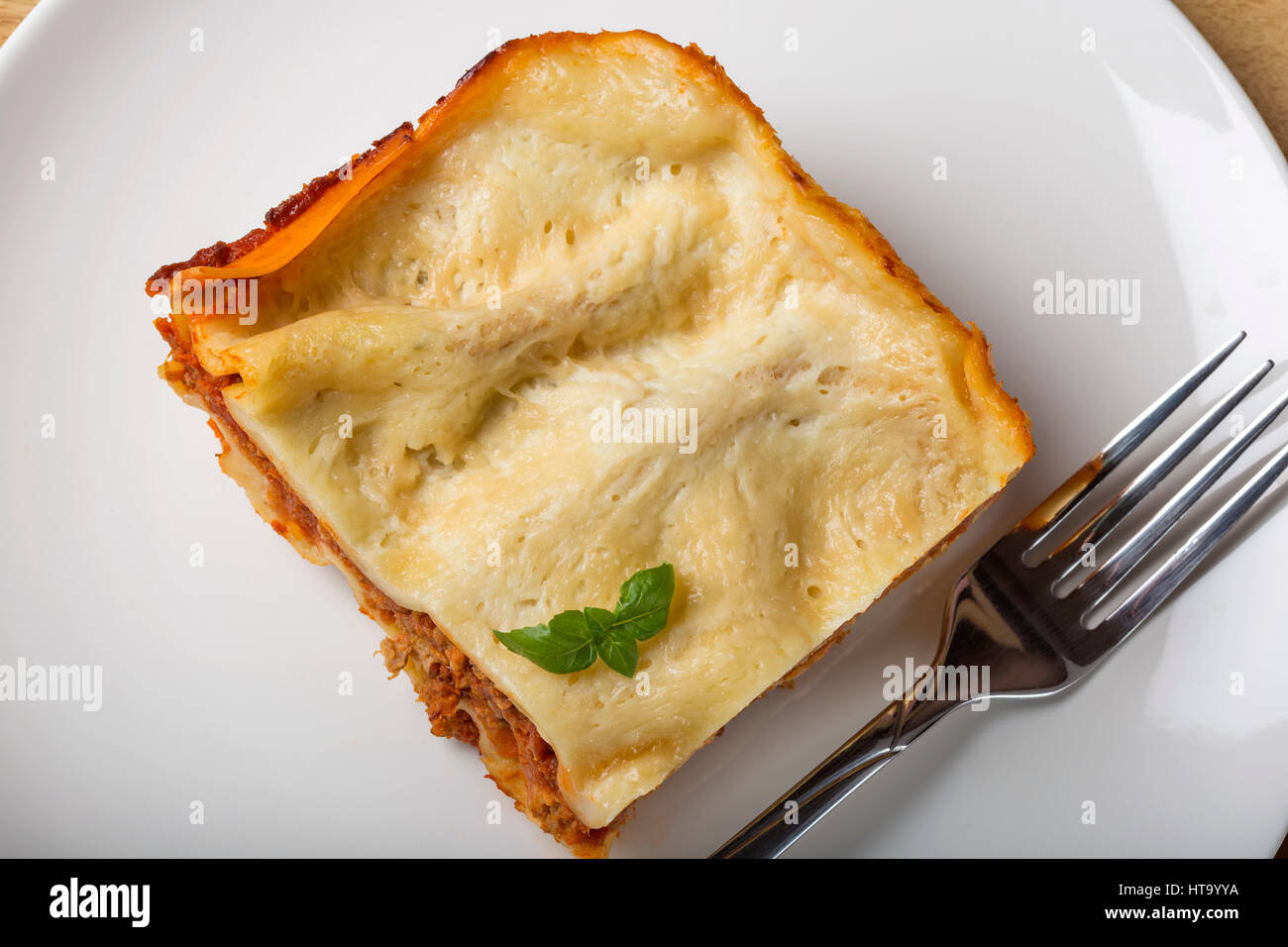 Casalingo italiano lasagne bolognesi sulla piastra bianca con forcella e basilico Foto Stock