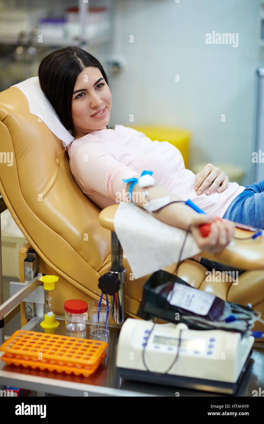 Sorridente ragazza distesa in poltrona durante hemotransfusion Foto Stock