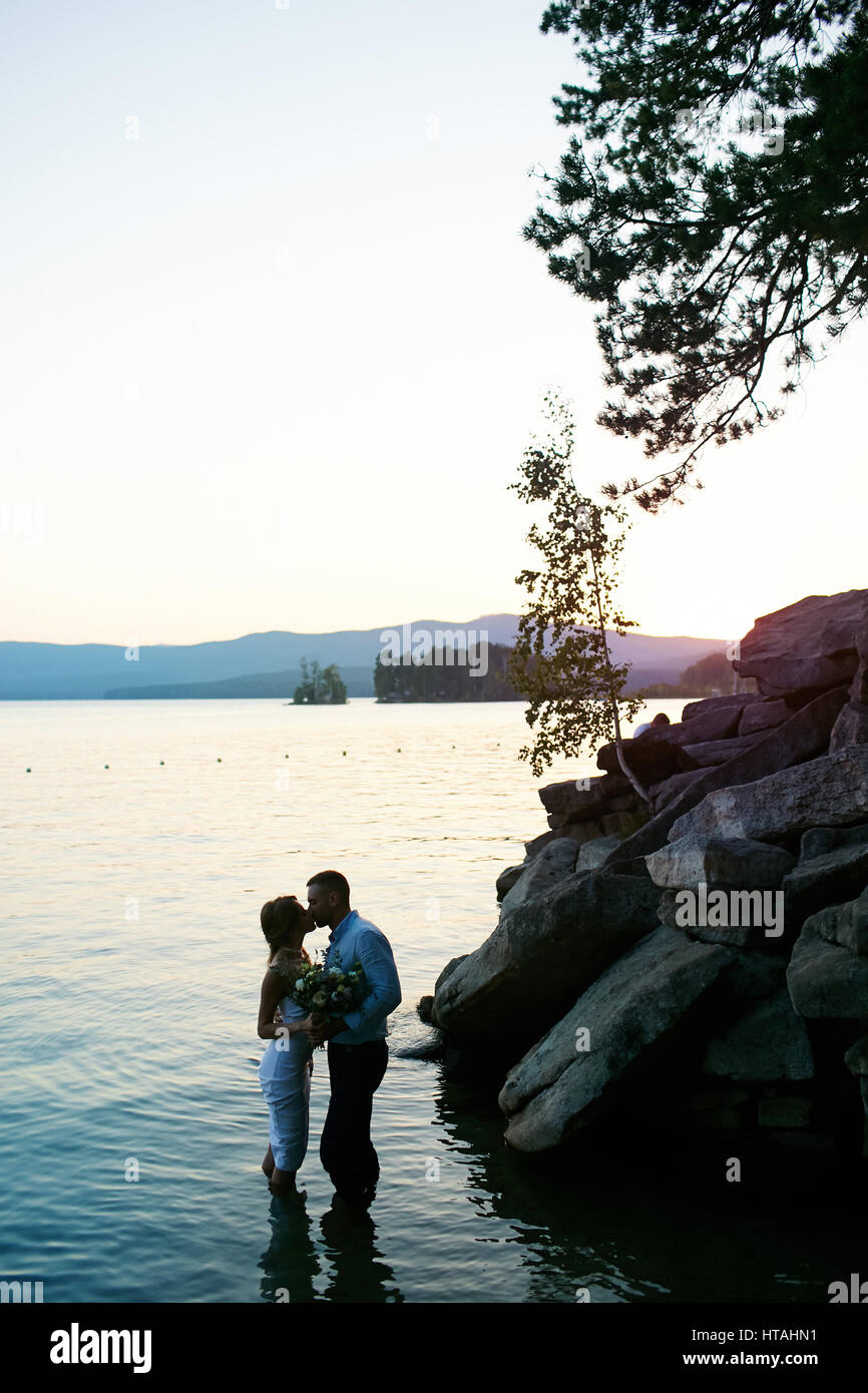 Coppia di sposi amoroso bacio al tramonto Foto Stock