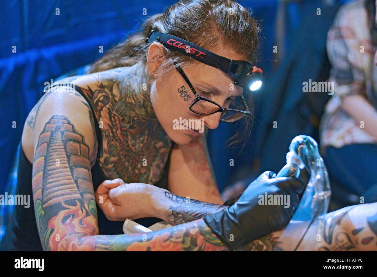 Una femmina tattoo artist applicando un tatuaggio per un un uomo di avambraccio a tattoo convention di Roseland in Midtown Manhattan, a New York City. Foto Stock