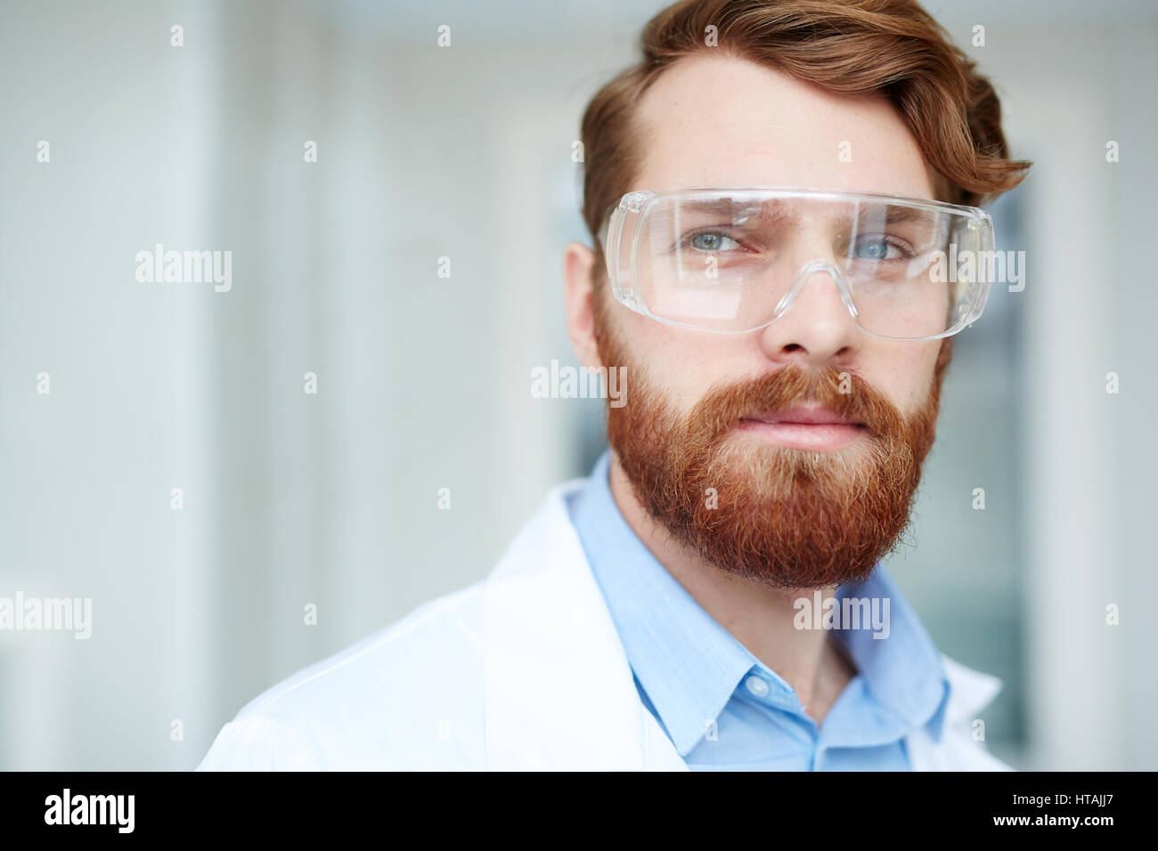 Medico in occhiali protettivi e camice bianco Foto Stock