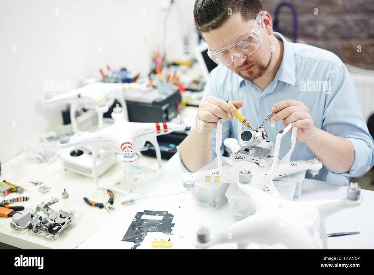 Ritratto dell uomo moderno lavorando su assemblaggio di più high tech fuchi e il fissaggio di telecamere in laboratorio di elettronica Foto Stock