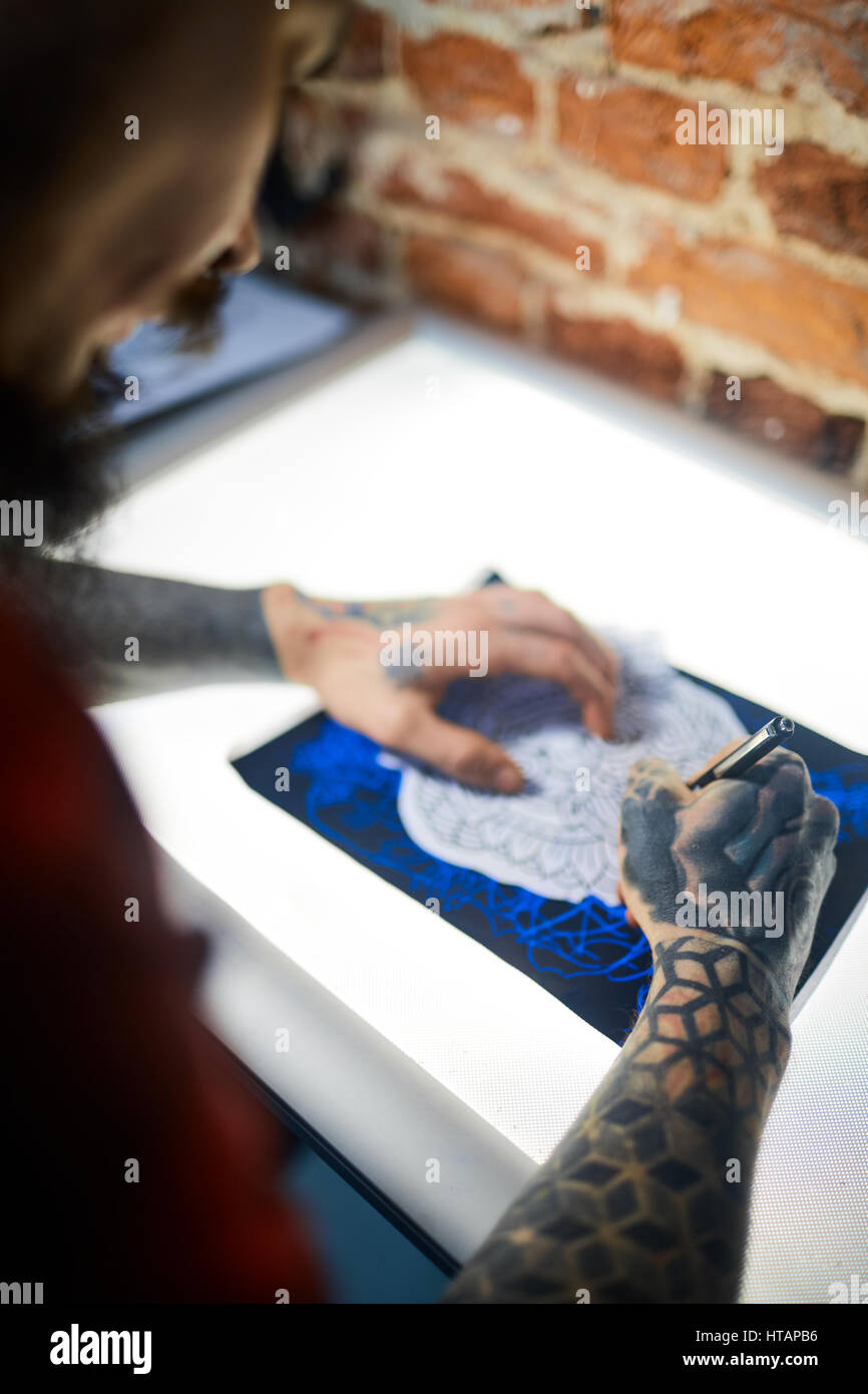 Le mani di uomo con tatuaggi disegno ornamento con penna Foto