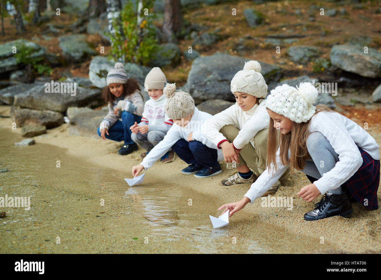 Adorabili compagni di classe a giocare la carta-barche da acqua Foto Stock