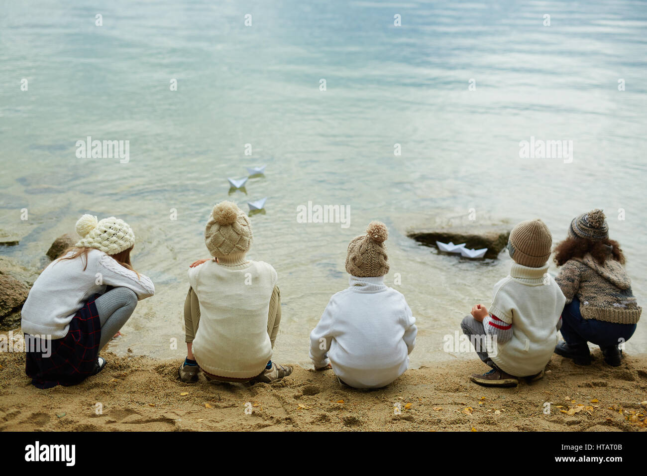 Vista posteriore di alcuni ragazzi osservando la carta-barche su acqua Foto Stock