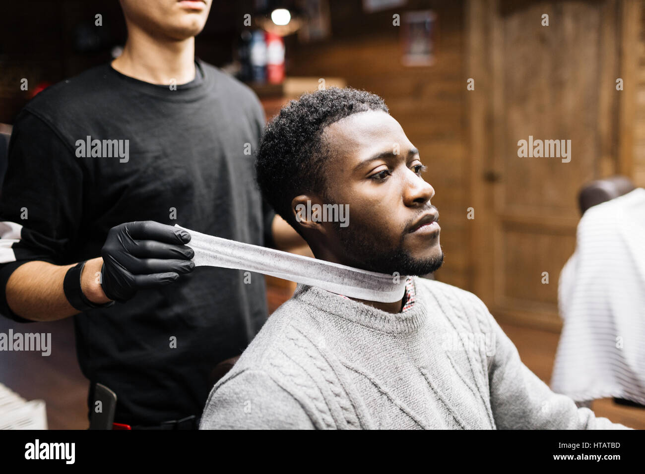 Haidresser mettere su carta speciale collare sul collo del suo cliente prima del taglio di capelli Foto Stock