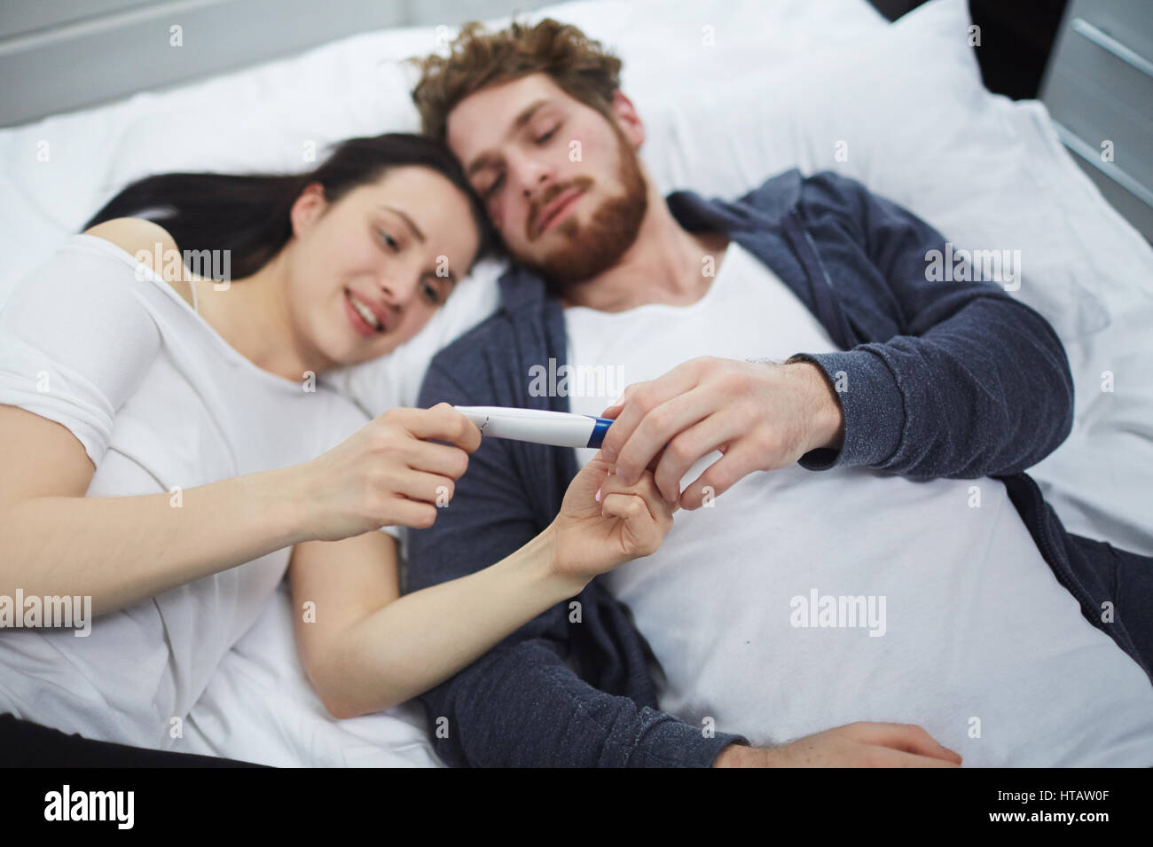Coppia giovane azienda test di gravidanza mentre giaceva a letto Foto Stock
