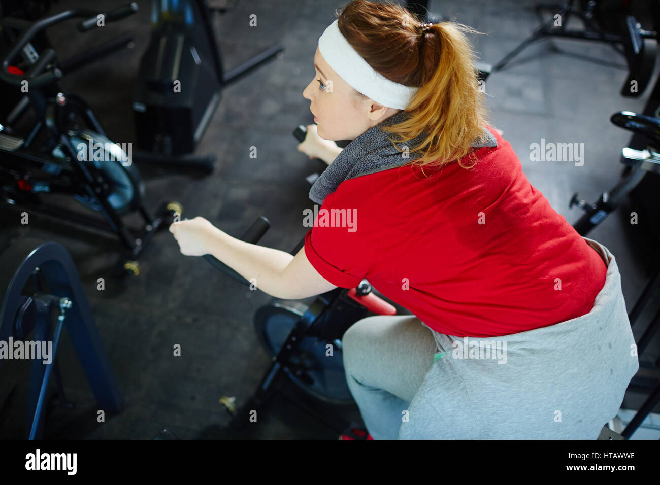 Vista sopra ritratto di soggetti obesi sudate donna determinata a perdere peso da lavoro su noleggio macchina in palestra Foto Stock