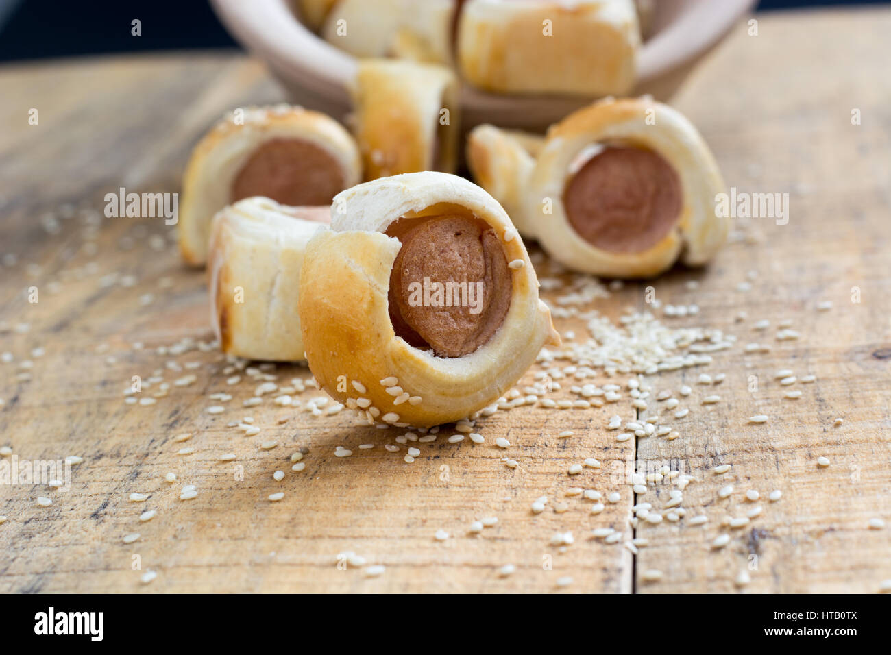 Fatta in casa i suini in una coperta. salsicce laminati in croissant pasta cotta raffreddamento su rack in metallo con sesamo. messa a fuoco selettiva Foto Stock