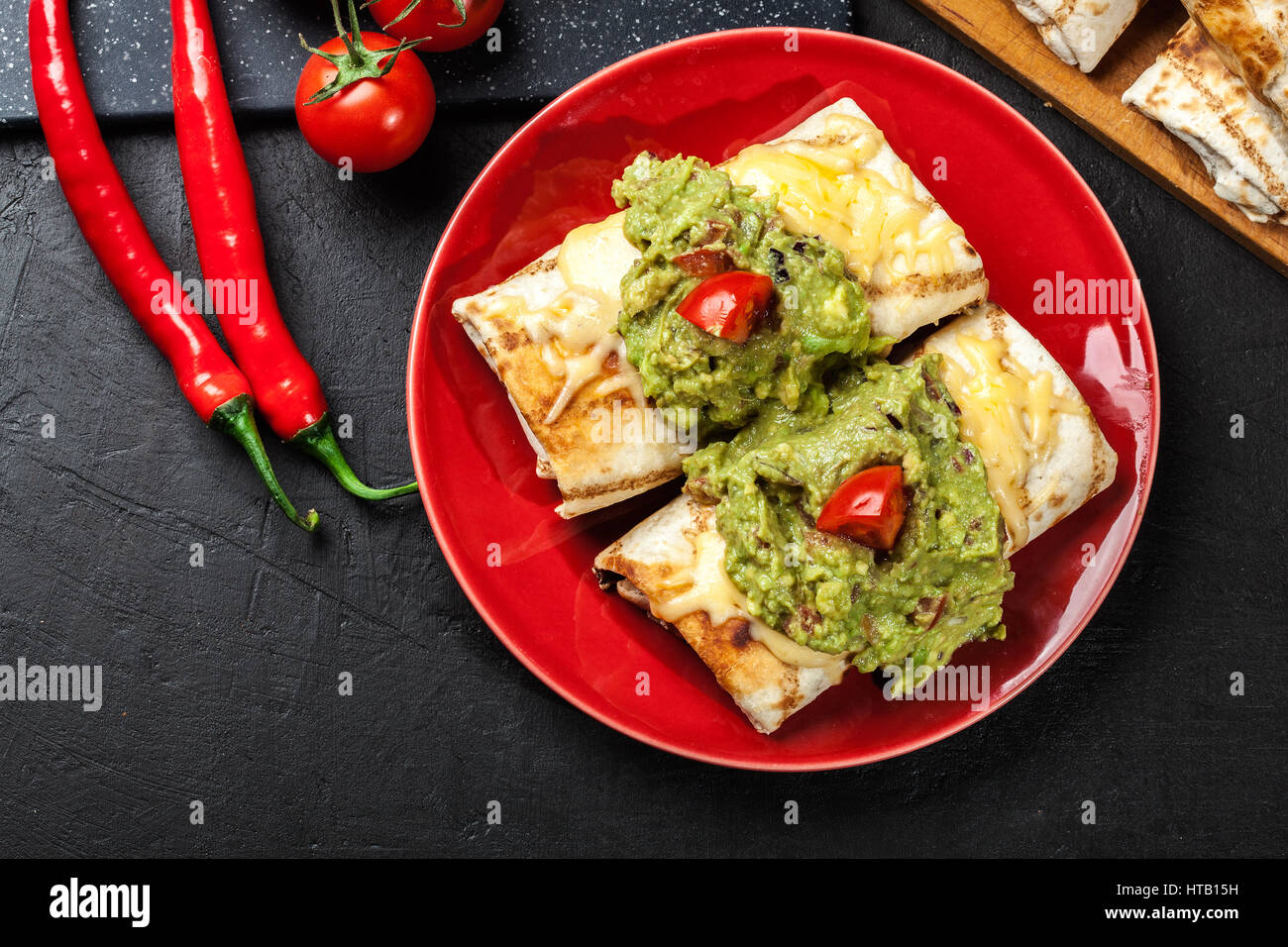 Chimichanga messicana con il guacamole dip su una targhetta rossa Foto Stock