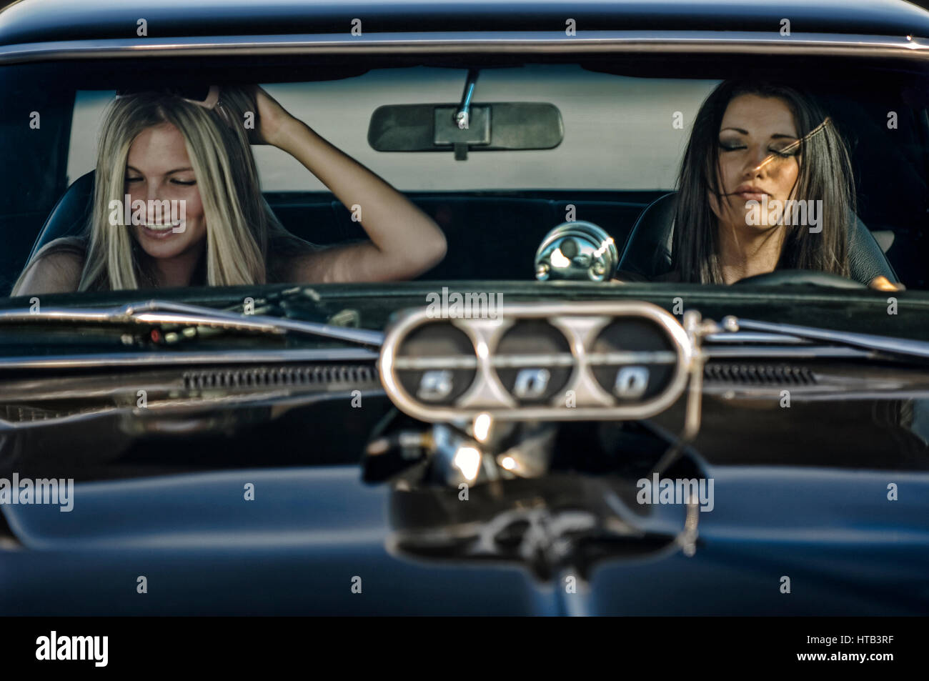 Due giovani donne di viaggiare a un vecchio americano auto d'epoca in un dietro le quinte del road movie Foto Stock