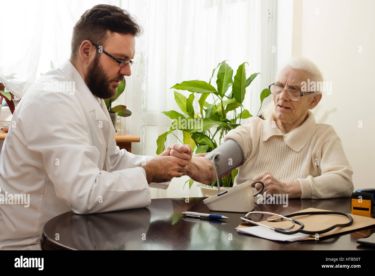 Un medico privato dell'ufficio. Geriatrician medico prende il paziente e misurare la sua pressione del sangue. Foto Stock