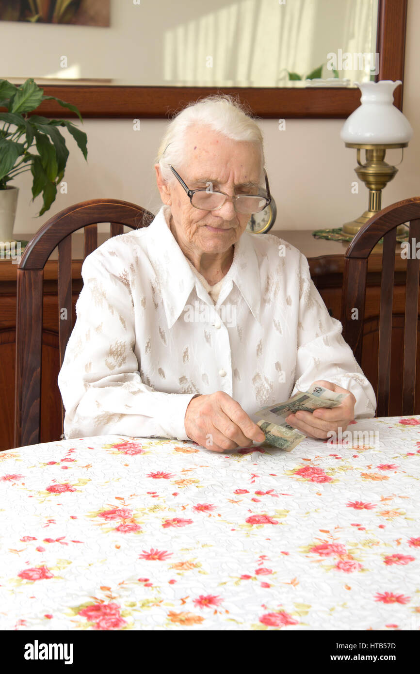 Pension. Vecchia donna conta il denaro. Vecchia donna con la faccia triste conta i soldi mentre è seduto al tavolo. Foto Stock