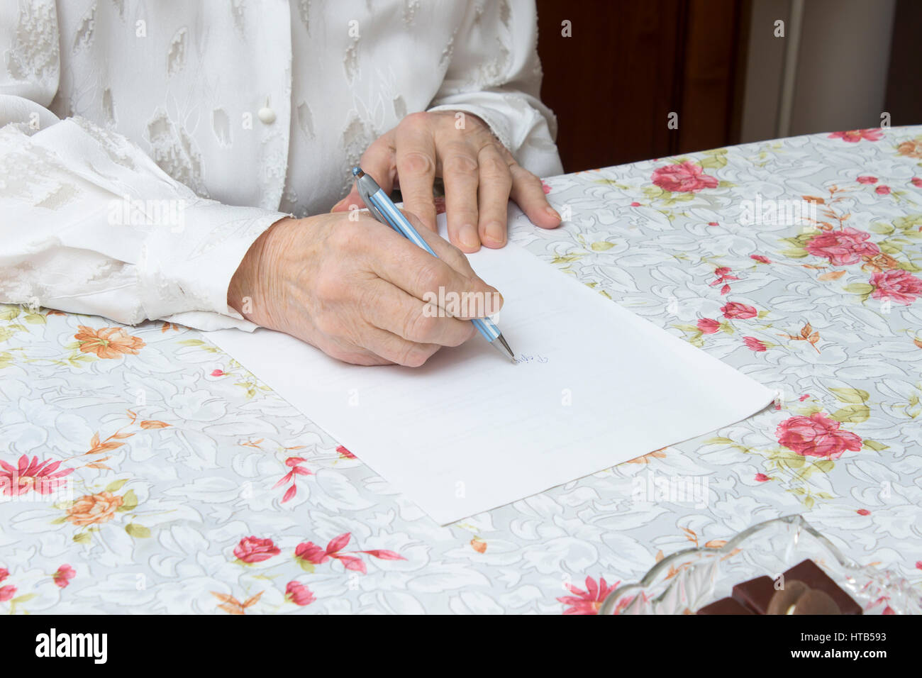 Le mani della vecchia donna che scrive il testamento scritto a mano su un pezzo di carta Foto Stock